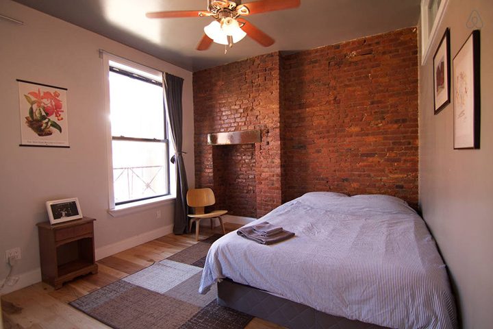 Egy brooklyni airbnb szállás hálószobája egy ággyal és rakott tégla fallal