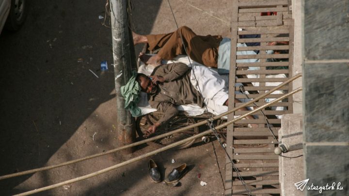 egy indiai férfi ébredezik miután a fa kocsiján aludt az utcán