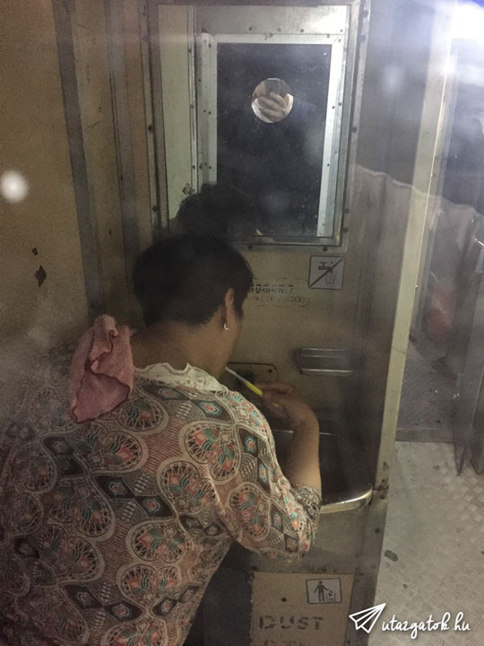 Japán turista nő fogat mos egy undorító vasuti kézmosóban, ahol még egy áthuzott pohár jel is ki van ragasztva