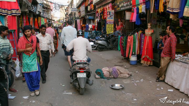 A bazársoron a forgalom közepén egy indiai asszony fekszik a földön az út közepén