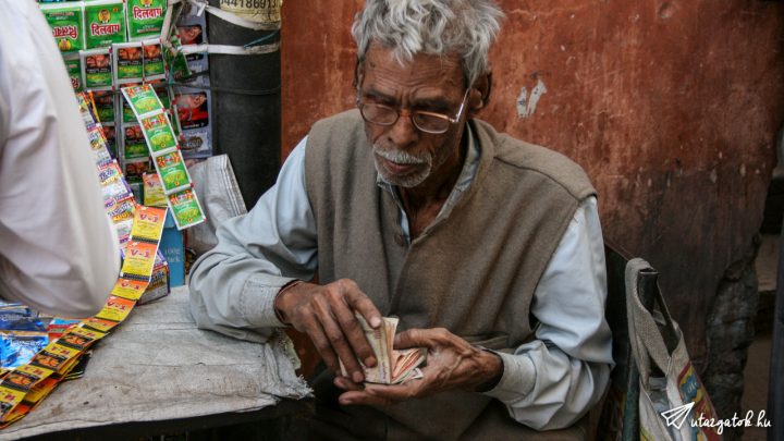 Idős indiai férfi számolja papírpénzét a tenyerében