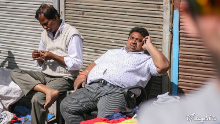 nagydarab kövér indiai ül egy irodai fotelben miközben telefonál