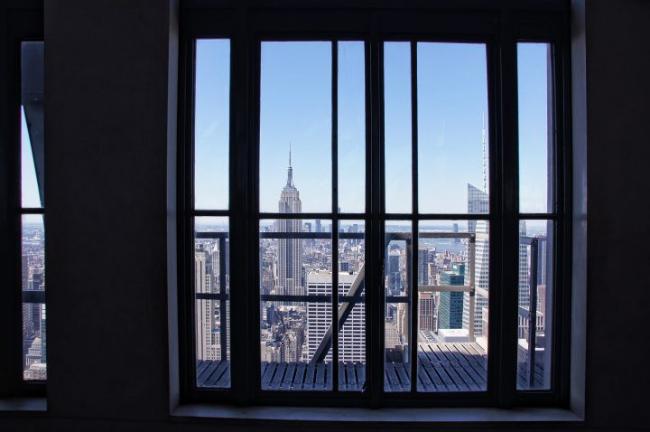 Nagy üvegablakon keresztül látszik az Empire State Building a messzeségben