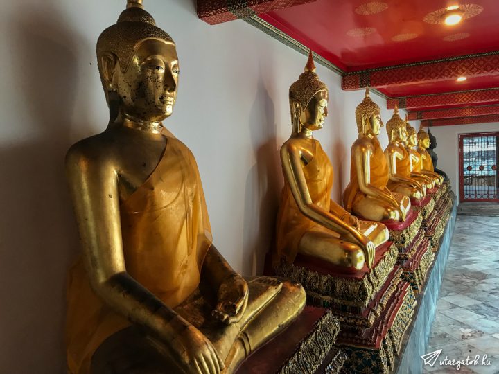 Buddha szobrok sorakoznak a fal mellett egymás után