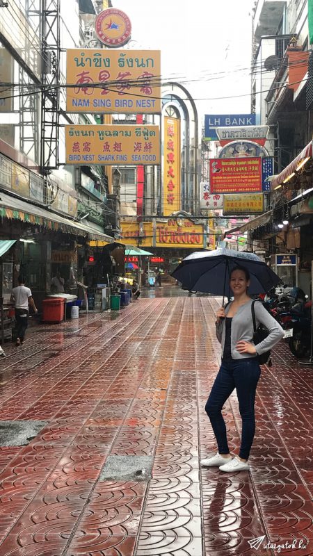 Kinga áll az esőben Bangkok kínai negyedében kezében esernyővel