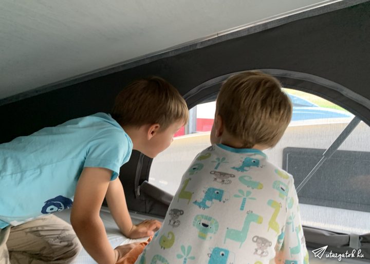 két kisgyerek fent a kinyitható sátortetőben néznek ki az ablakon