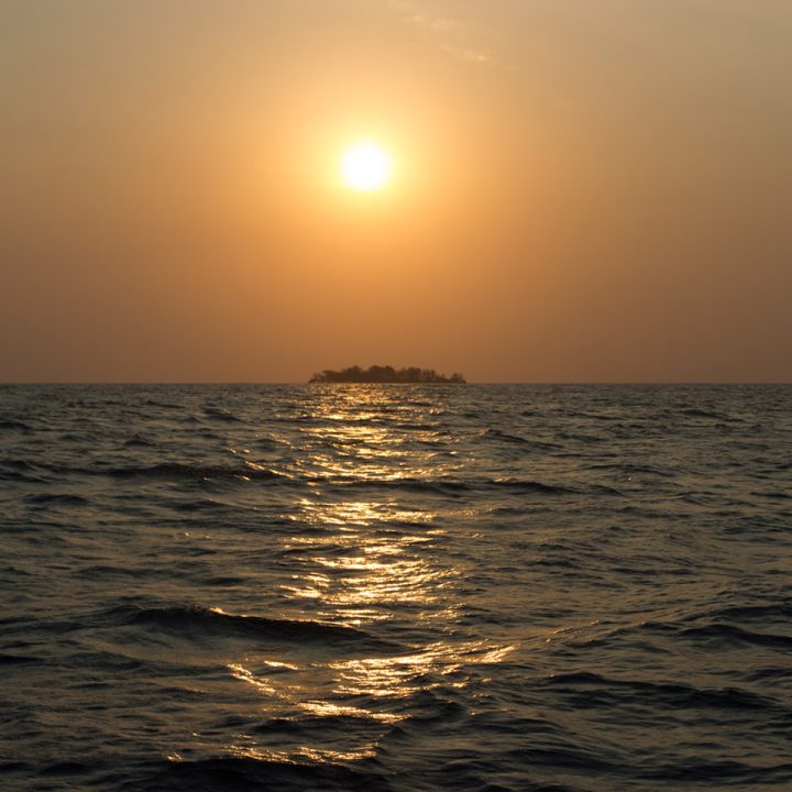 naplemente a tengeren, háttérben egy kicsi szigettel